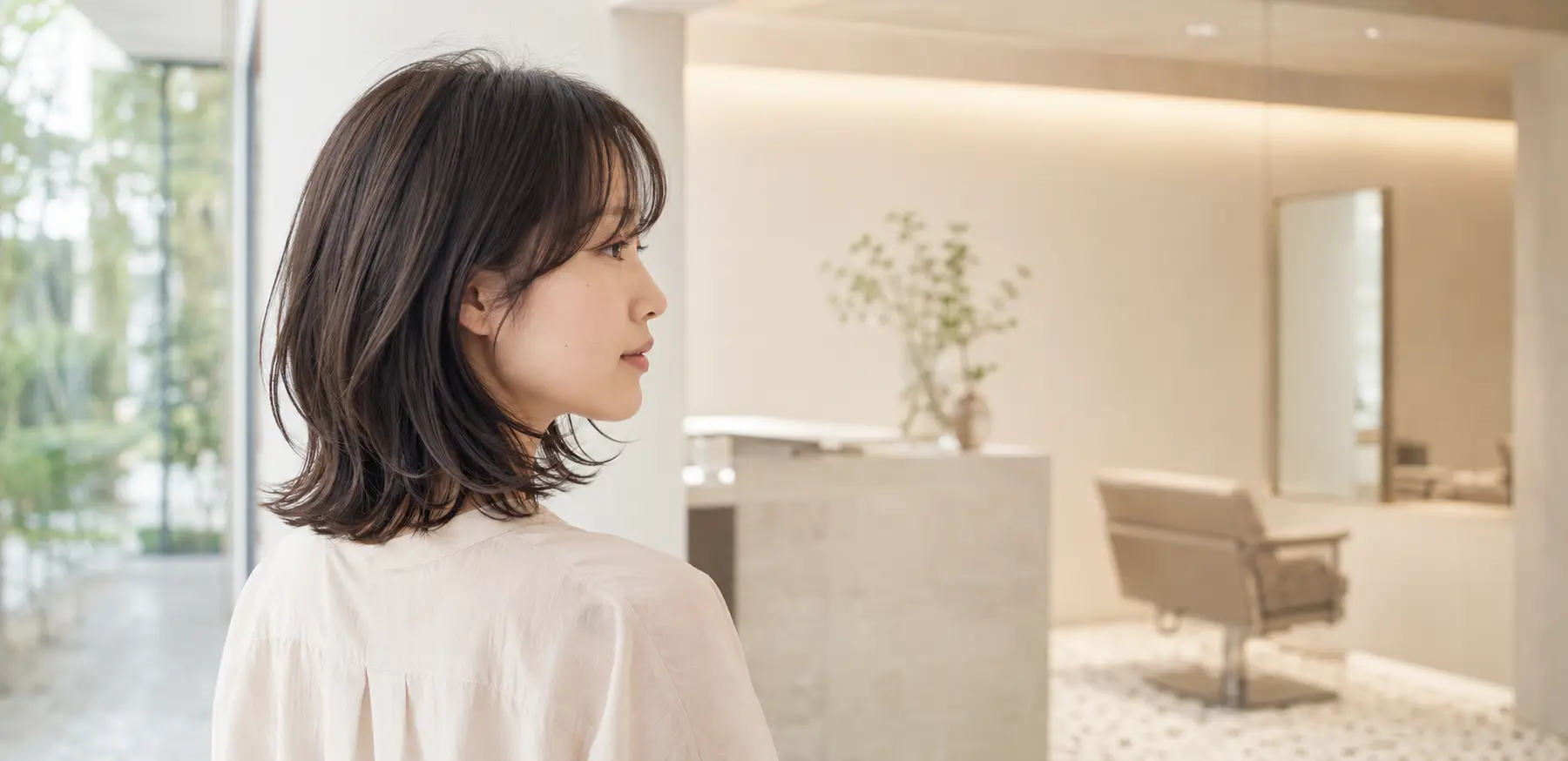 自然光が差し込む美容室で、柔らかなボブヘアの女性